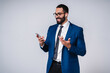 © InsideCreativeHouse - Attractive young Arabian businessman is excited with his mobile phone in formal suit isolated over grey background
