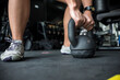 © Mdv Edwards - An anonymous woman grabs a heavy kettlebell on the floor in preparation for a workout at the gym.