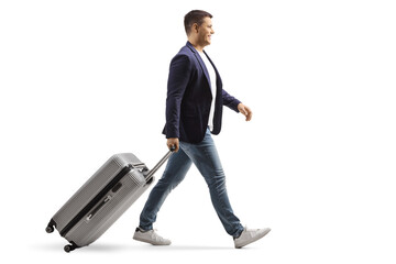 Canvas Print - Full length profile shot of a young man smiling and walking with a suitcase