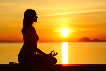 Wall Mural - Silhouette of a woman doing yoga exercise at sunset