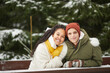 © AnnaStills - Portrait of young couple embracing and smiling at camera sitting at the table with snowy trees in the background