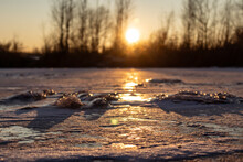 Orange Vivid Sunset On Icy Frozen Glossy Lake With Shallow Depth Of Field, Long Shadows. Selected Focus And Blurred Background