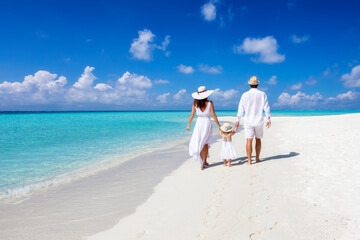 a beautiful family walks together on a tropical paradise beach in the maldives with turquoise ocean 
