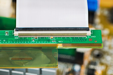 Plastic flexible circuit board for LCD panels and white ribbon cable. Green flat PCB detail with connector. Parallel transmission of many data signals with time-division multiplexing. Selective focus.