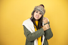 Young Beautiful Woman Wearing A Hat And A Green Winter Coat Over Yellow Background Suffering Pain On Hands And Fingers, Arthritis Inflammation