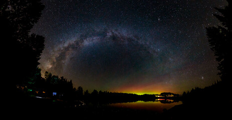 Wall Mural - A dramatic panorama of the Milky Way Galaxy and the Northern Lights (Aurora Borealis) high in the night sky above a lake at Algonquin Park, Ontario, Canada