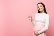 young pretty pregnant woman with glass of water isolated on pink