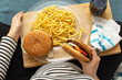 © Ersin - Cropped image of young hungry pregnant woman eating a hamburger and fried potatoes. Concept of unhealthy nutrition during pregnancy, Mother waiting baby. Close-up of belly and junk food (fast food).