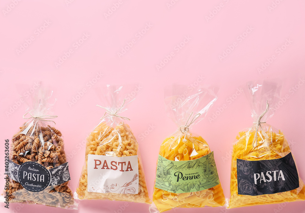 Bags with uncooked pasta on color background