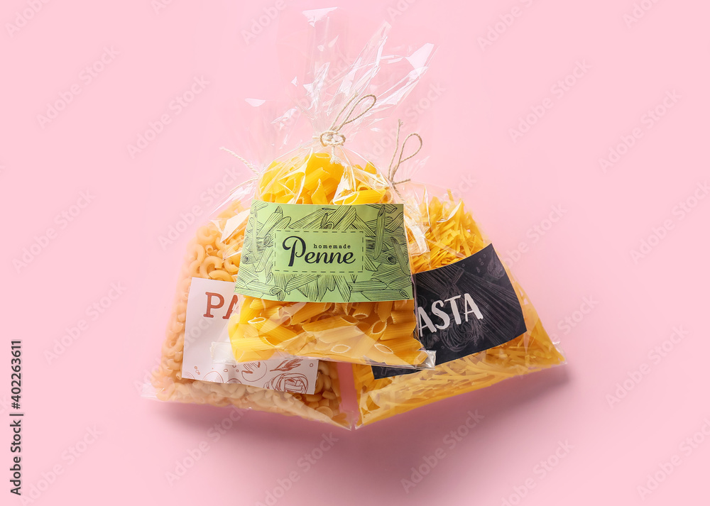 Bags with uncooked pasta on color background