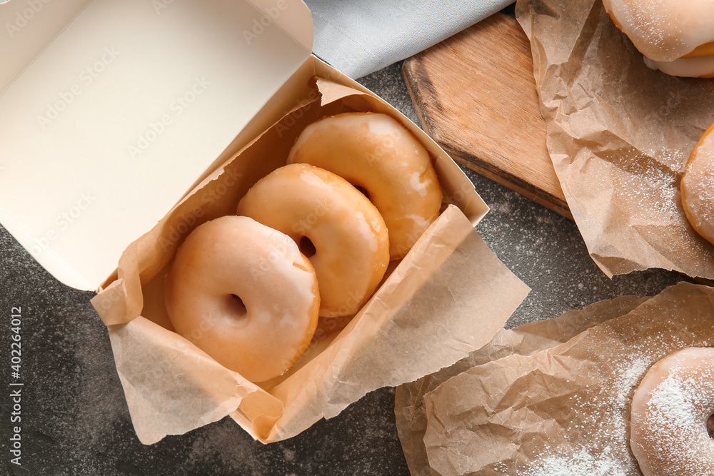 Box with tasty donuts on table