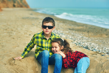 Two children on a walk by the sea on a cool day