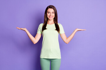 Wall Mural - Photo portrait of cheerful girl keeping empty spaces on both palms isolated on vivid violet color background
