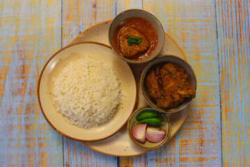 Rice with chicken kosha and fish curry with green chilies and onion