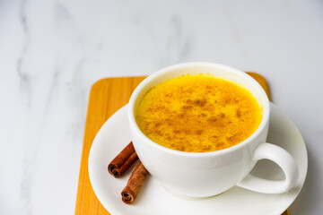 Turmeric golden spicy latte in white cup on marble table