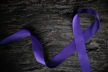 Top view of  violet ribbon on dark wood background with copy space. Hodgkin lymphoma cancer awareness  concept.