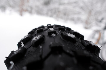  Studded bicycle tire with snow.
Fat bike winter tire with spikes close-up shallow depth of field. 
