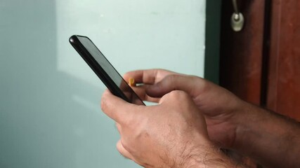 Close-up of a man typing a text message on a smartphone with a cigarette in his hand. Slow motion FullHD footage