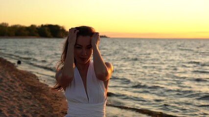 Wall Mural - Beautiful young woman posing on the beach in a white dress