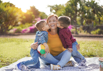 Happy family enjoy day in nature park with a pic nic - Twin sons kissing mother outdoor