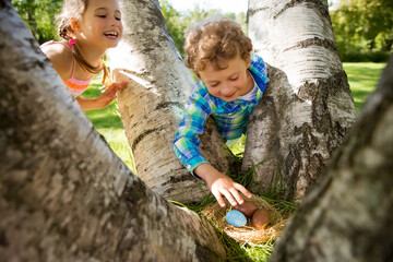 Wall Mural - Cute boy and girl celebrating Easter, searching and eating chocolate eggs. Happy family holiday. Happy kids laughing, smiling and having fun. Beautiful spring sunny day in park