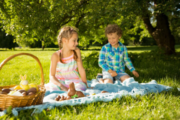 Wall Mural - Cute boy and girl celebrating Easter, searching and eating chocolate eggs. Happy family holiday. Happy kids laughing, smiling and having fun. Beautiful spring sunny day in park