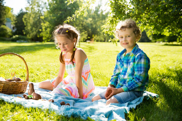 Wall Mural - Cute boy and girl celebrating Easter, searching and eating chocolate eggs. Happy family holiday. Happy kids laughing, smiling and having fun. Beautiful spring sunny day in park