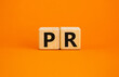 PR - public relations symbol. Wooden cubes with words 'PR, public relations' on beautiful orange background, copy space. Business and PR - public relations concept.