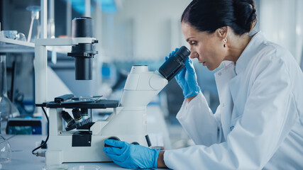 Wall Mural - medical development laboratory: portrait of beautiful caucasian female scientist looking under micro