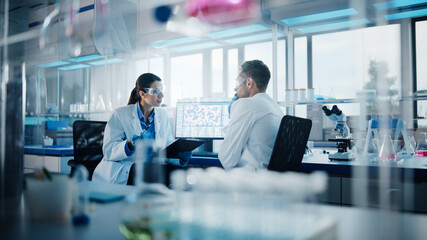 Wall Mural - modern medical research laboratory: portrait of two scientists working, using digital tablet, analyz