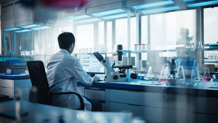 Wall Mural - medical development laboratory: back view of japanese male scientist using touch screen digital tabl