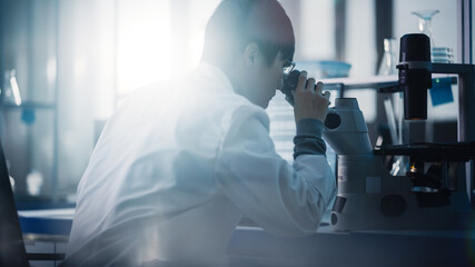 Wall Mural - medical development laboratory: portrait of east asian scientist looking under microscope, analyzes 