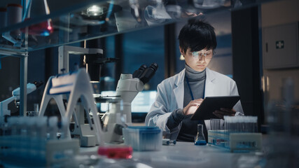 Wall Mural - medical development laboratory: east asian scientist uses digital tablet computer, uses microscope, 