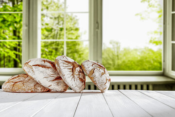 Wall Mural - Fresh bread on a white table on a beautiful warm day