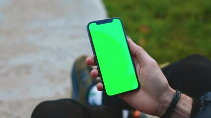 shot of man hands use phone with vertical green screen outdoors. sitting. touchscreen finger interne