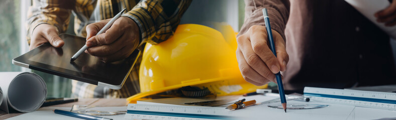 Two colleagues discussing data working and tablet, laptop with on on architectural project at construction site at desk in office