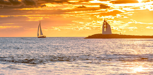 Wall Mural - Panorama d'un coucher de soleil sur une digue avec vue sur le phare de La Grande Motte, sud de la France près de la Camargue.