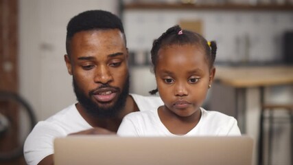 African american father and daughter using laptop at home together