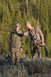 father and son hunting together in woods with compound bows