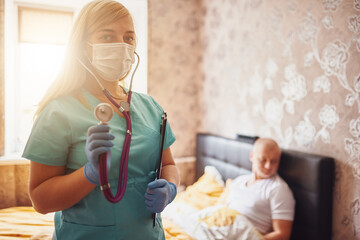 House call. Doctor visit at home. Examination of the patient. Portrait of a nurse wearing a mask, gloves and with a stentoscope