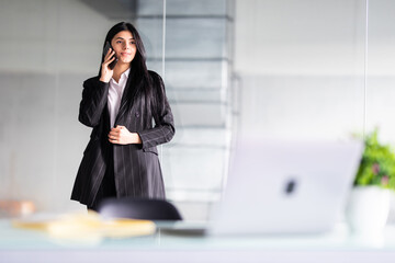 Young smiling business woman talking on the phone in office