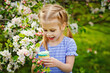 © Elena  - A child in a blooming apple orchard enjoys a warm spring day. The girl holds a cake in her hands, wants to eat it.