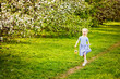 © Elena  - Beautiful girl in a blooming apple orchard enjoying a warm spring day. A child walks along the path with a basket in his hands.