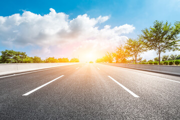 Asphalt road and green forest under blue sky.