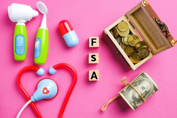 Wooden block written FSA or Flexible Spending Account with medical toy, gold chest and fake money. One of a number of tax-advantage financial accounts, resulting in payroll tax savings. 