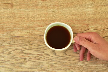 hand  holding black coffee cup on table