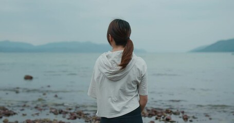 Poster - Woman look at the sea and stand on the beach