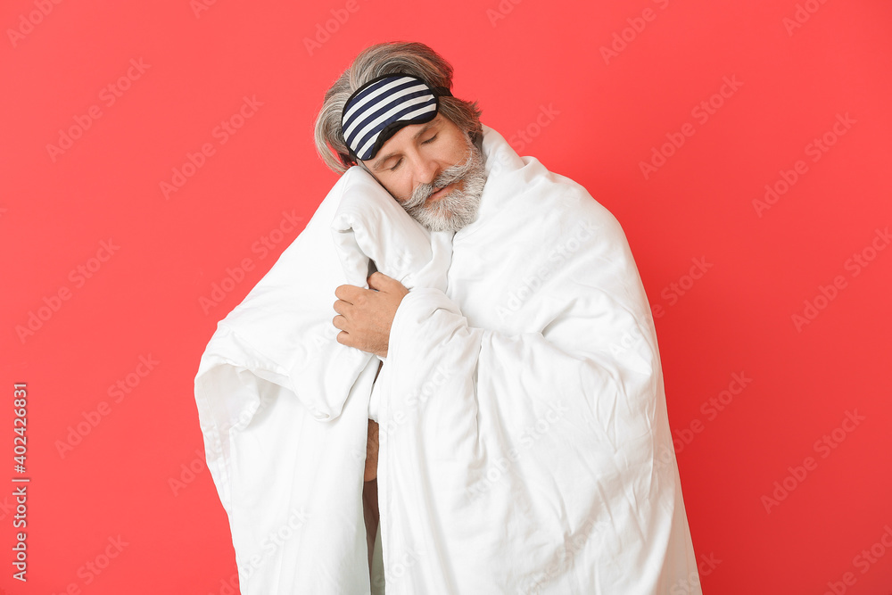Mature man in sleep mask on color background
