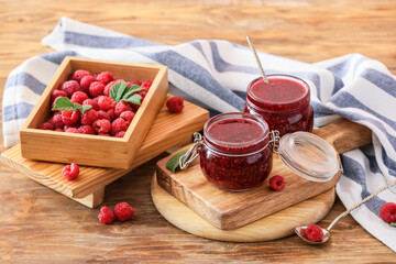 Jars with sweet raspberry jam on table