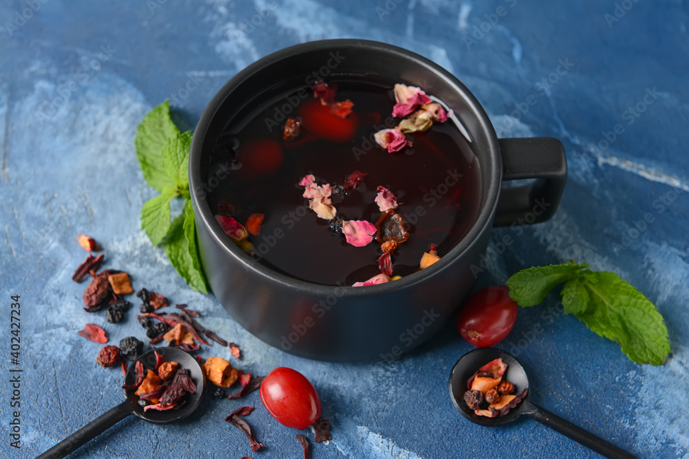 Cup with floral tea and barberry on color background